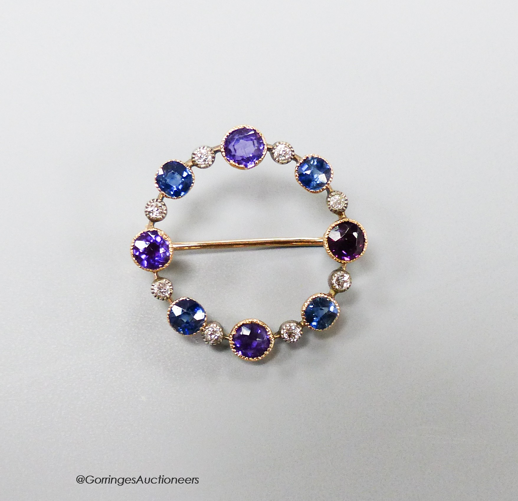 An early 20th century yellow metal, amethyst, sapphire and diamond chip set openwork circular brooch, 27mm, gross 3.9 grams.